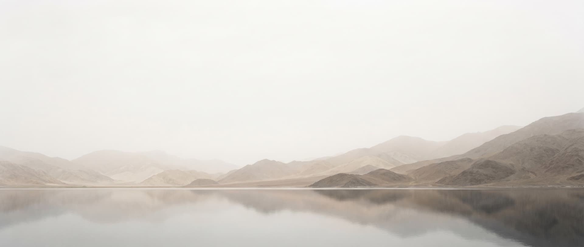 Misty mountain range mirrored in still water